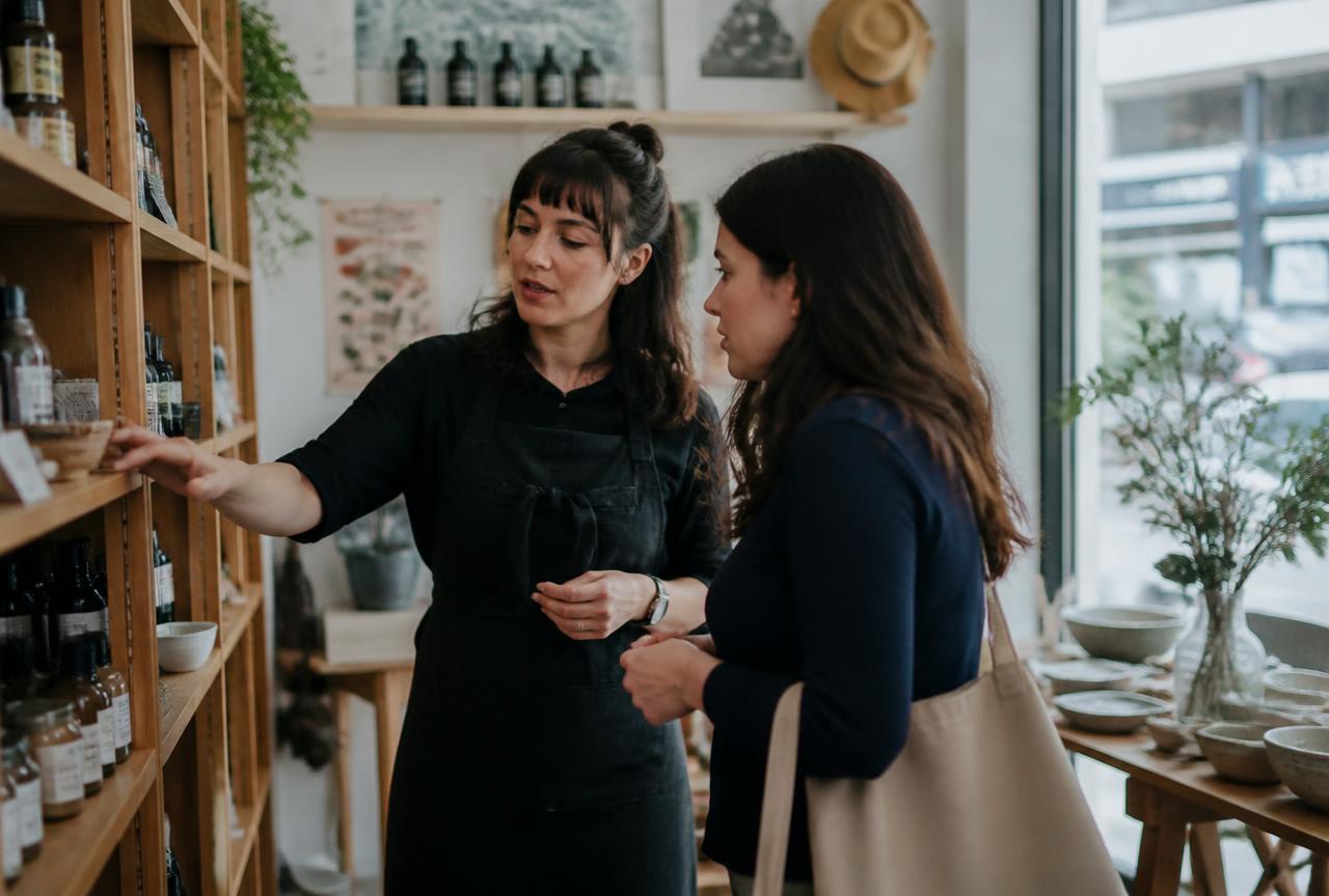 A shop owner helping a customer choose products in a small local store